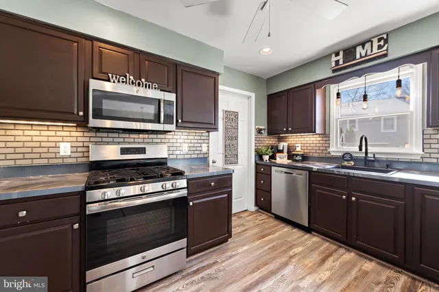 a kitchen with kitchen island granite countertop a sink cabinets and stainless steel appliances