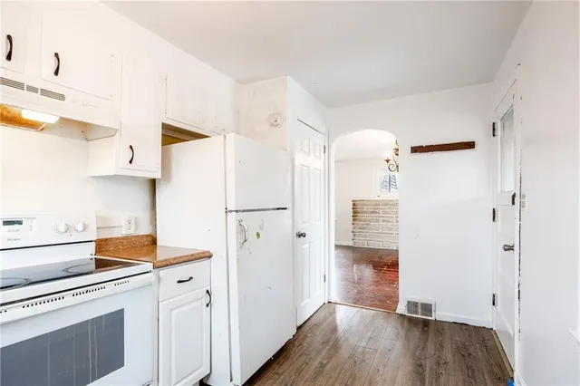 a kitchen with a refrigerator a stove and wooden floor