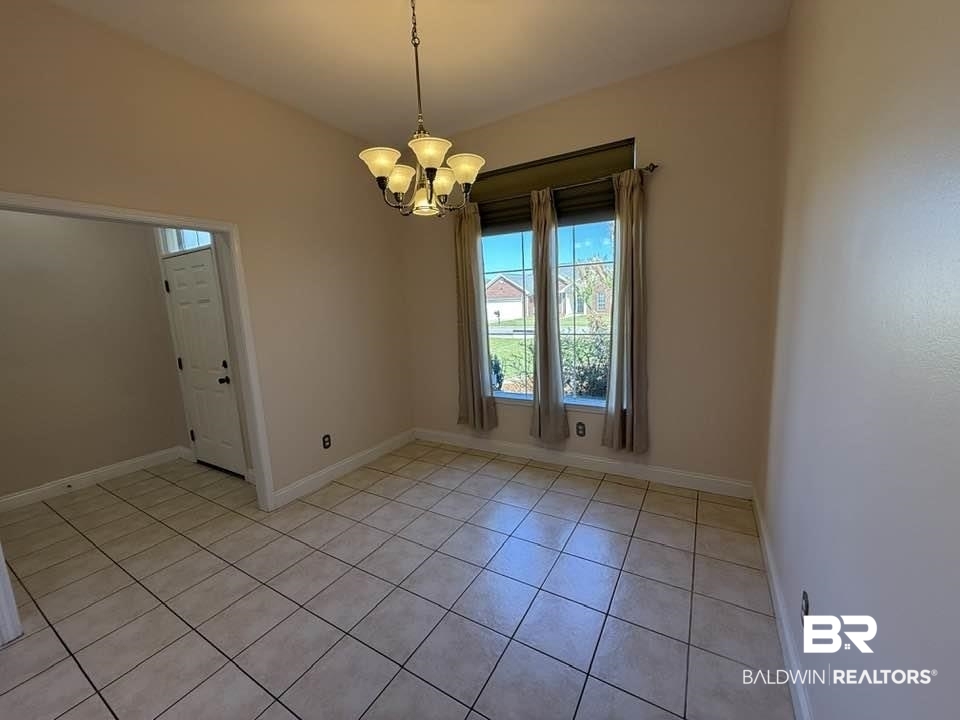 10428 South Side Loop Fairhope, AL 36532 - Photo 12 of 28 Empty room with baseboards, light tile patterned flooring, and an inviting chandelier