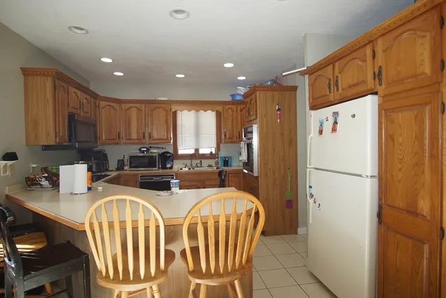 a kitchen with stainless steel appliances granite countertop a refrigerator a stove a sink a dining table and chairs