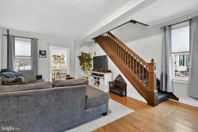 a living room with furniture and hard wood floor and windows