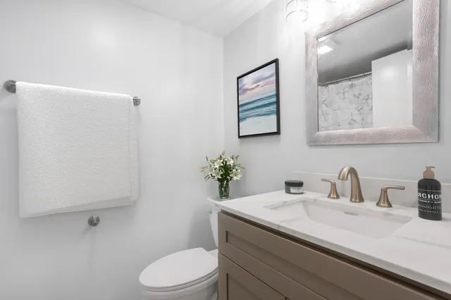 a bathroom with a granite countertop toilet sink and mirror