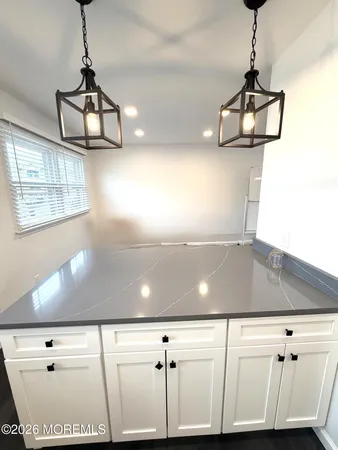 a room with a chandelier fan and wooden floor