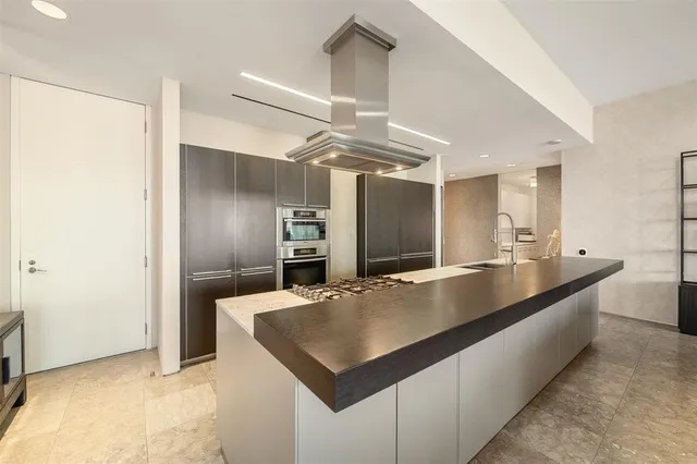 a large kitchen with kitchen island a large counter top and stainless steel appliances