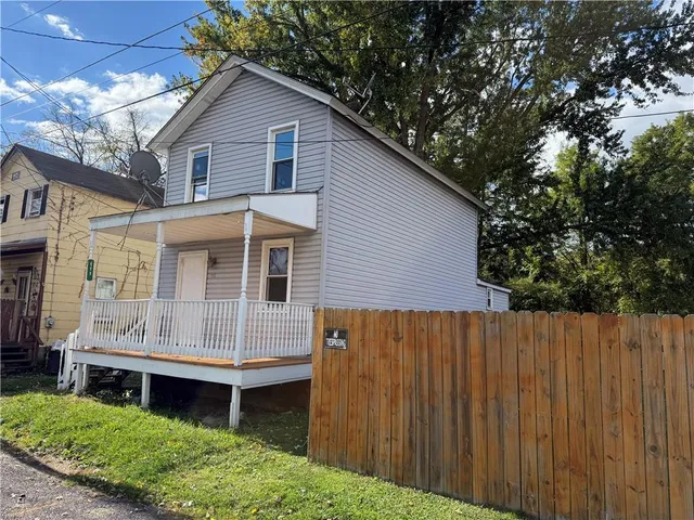 a front view of a house with a yard and wooden fence