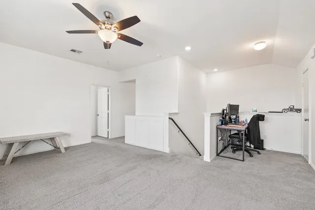a view of a workspace with furniture and a ceiling fan