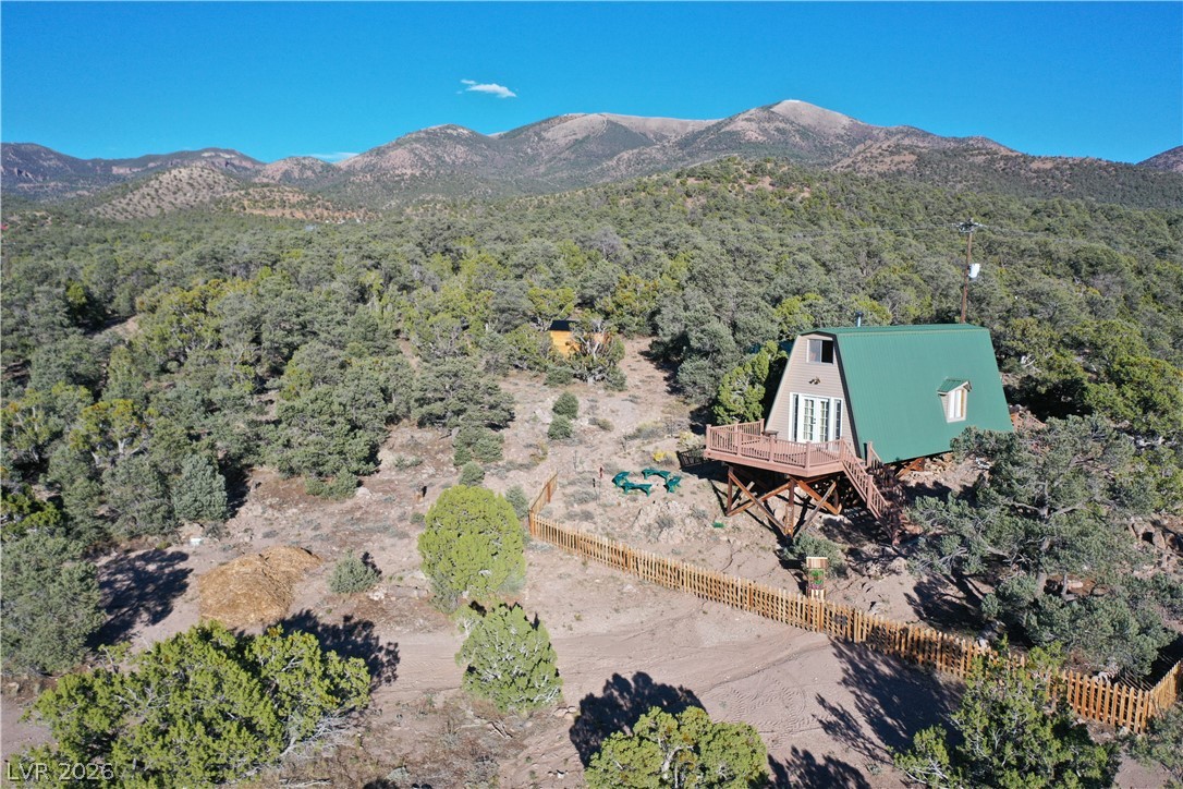 20502 Windsong Road Pioche, NV 89043 - Photo 28 of 30 An elevated wooden deck extends from this unique A-frame cabin set against a mountain backdrop.