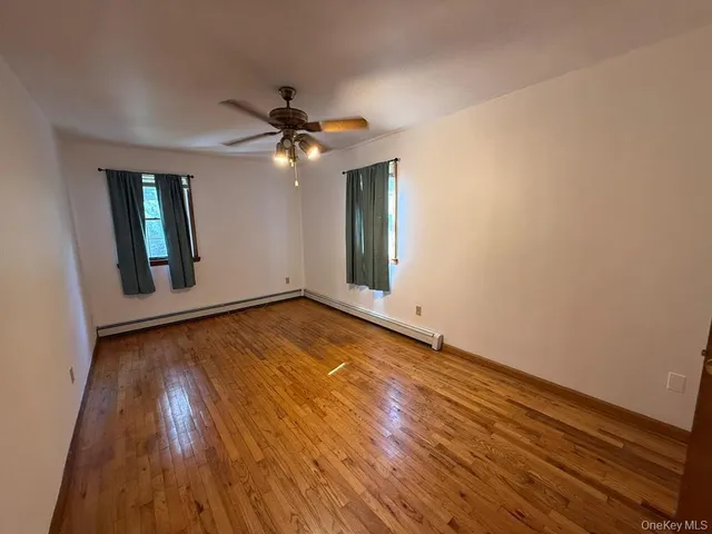 an empty room with wooden floor chandelier fan and windows
