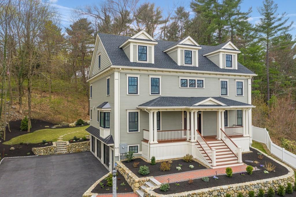 a view of a white house with a large windows and a yard with plants and seating space