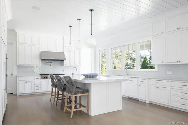 a kitchen with kitchen island granite countertop a sink a stove a dining table and chairs