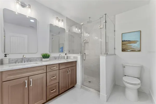a spacious bathroom with a granite countertop sink a toilet a shower and a mirror