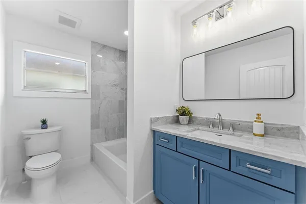 a bathroom with a granite countertop toilet sink and mirror