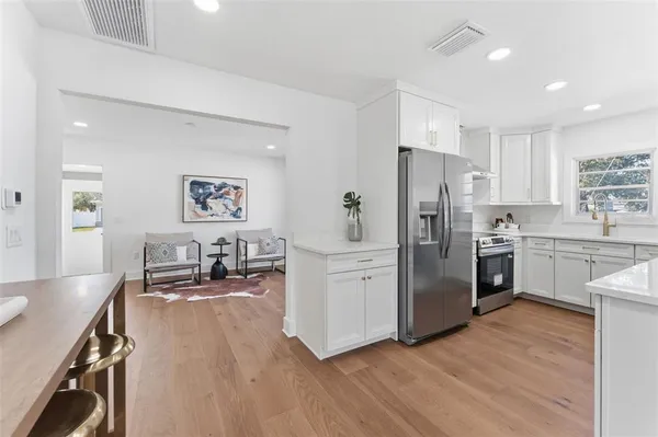 a kitchen with stainless steel appliances a sink a stove a refrigerator cabinets and wooden floor