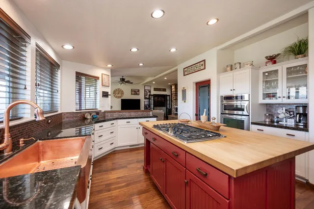 a kitchen with stainless steel appliances granite countertop a stove a sink dishwasher and a refrigerator with wooden floor