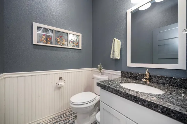 a bathroom with a granite countertop sink mirror and toilet