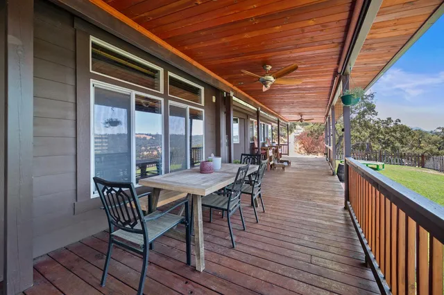 a patio with wooden floor a yard a table and chairs