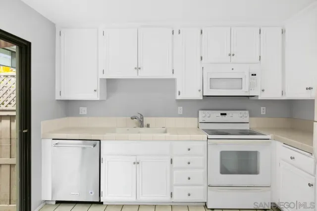 a kitchen with white cabinets and white appliances
