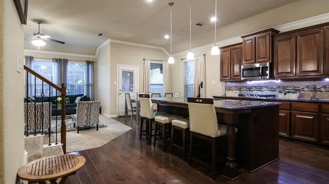 a kitchen with stainless steel appliances kitchen island granite countertop a table chairs and a refrigerator