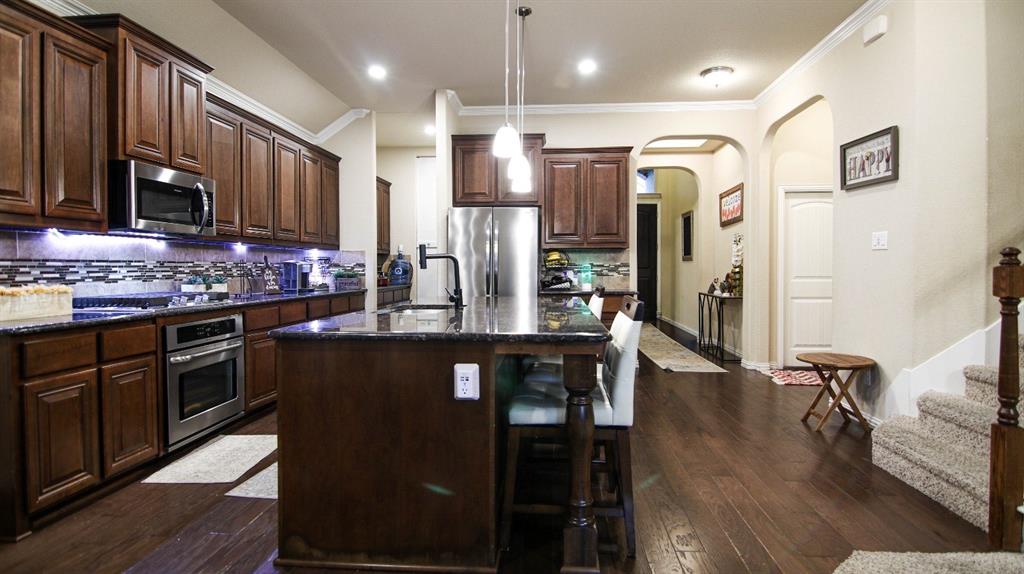 9917 Bodega Bay Road Fort Worth, TX 76177 - Photo 4 of 18 a kitchen with stainless steel appliances granite countertop a stove a refrigerator a sink a dining table and chairs with wooden floor