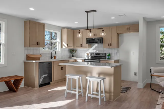 a kitchen with kitchen island granite countertop a sink a stove a refrigerator and island with wooden floor