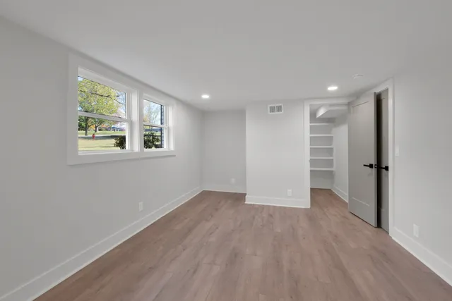 a view of an empty room with wooden floor and a window