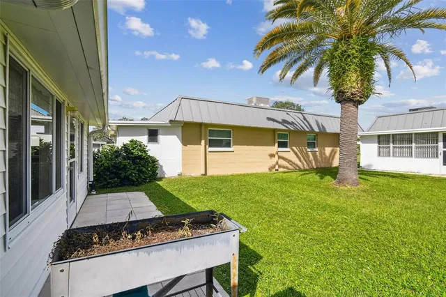 a view of a house with a big yard potted plants and large tree
