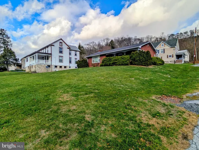 a view of a big house with a big yard and large trees