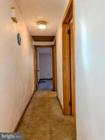 a view of a hallway with wooden floor and a bathroom