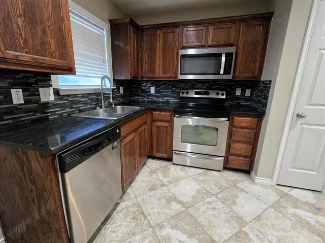 a kitchen with stainless steel appliances granite countertop a stove microwave and sink