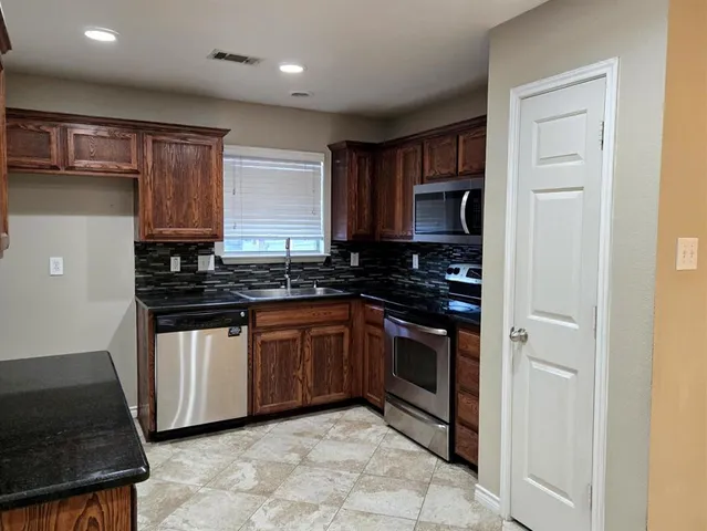 a kitchen with granite countertop a stove sink and cabinets