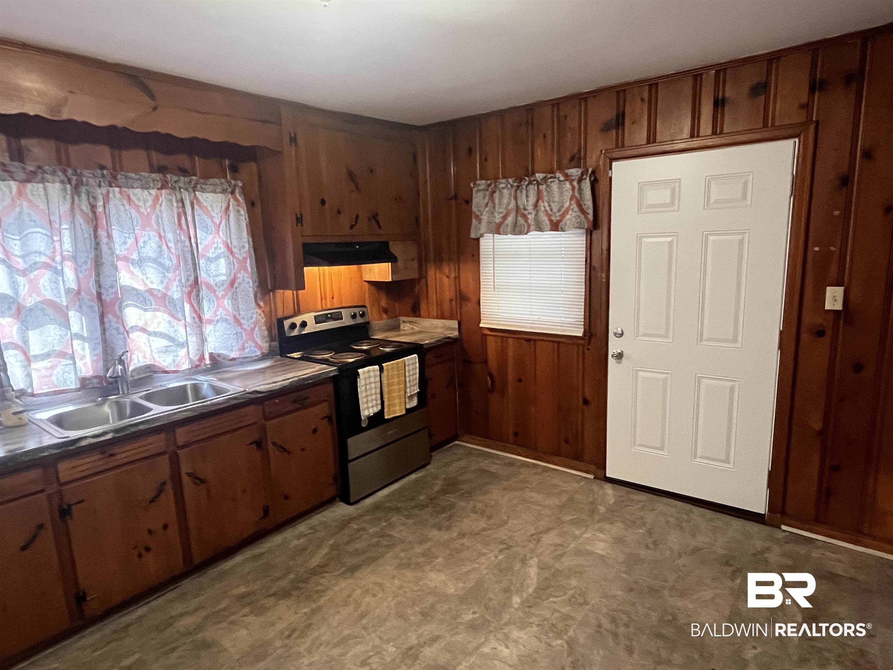 5055 Overlook Road Mobile, AL 36618 - Photo 6 of 28 Kitchen with stainless steel electric range, wooden walls, ventilation hood, brown cabinets, and dark countertops