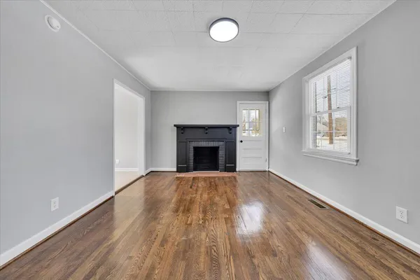 an empty room with wooden floor and fireplace
