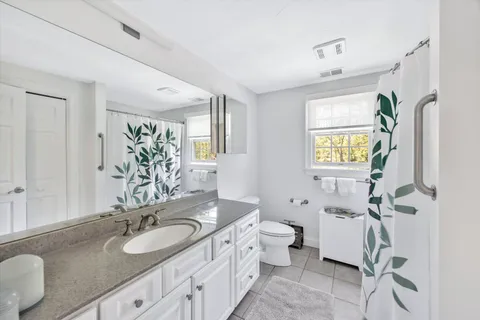 a bathroom with a granite countertop double vanity sink mirror and toilet
