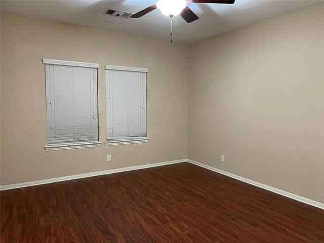 a view of an empty room with wooden floor chandelier fan