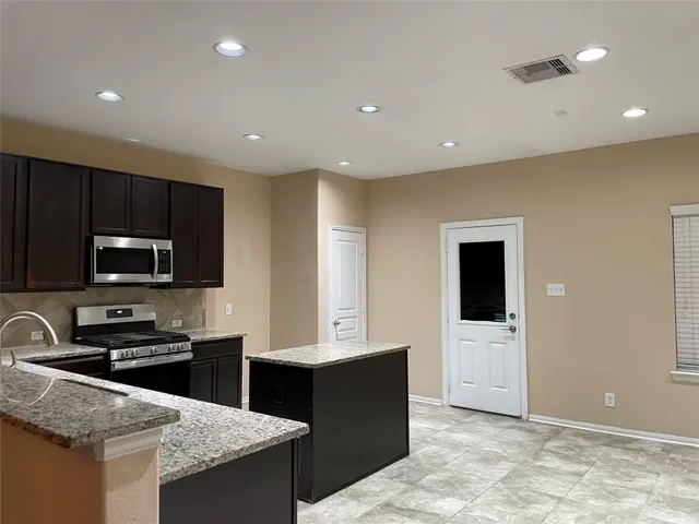 a large kitchen with kitchen island a sink stainless steel appliances and cabinets