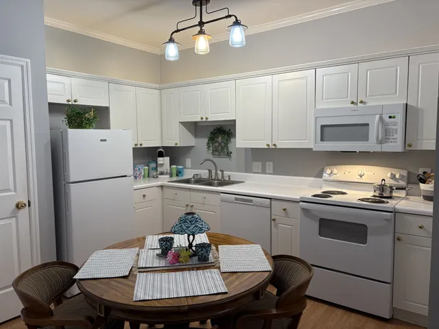 a kitchen with stainless steel appliances granite countertop a dining table chairs refrigerator and sink