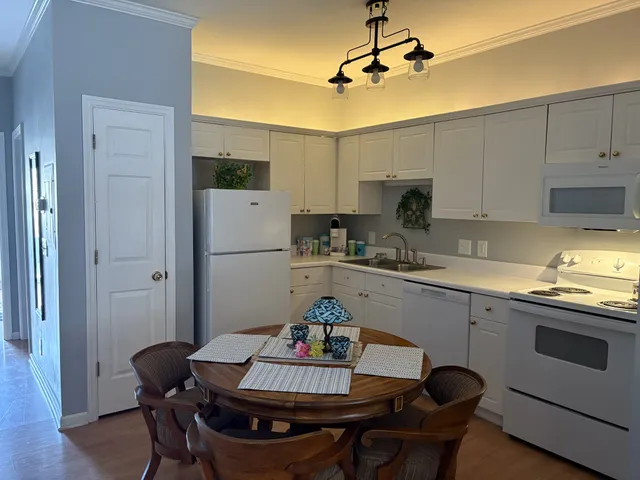 a kitchen with stainless steel appliances granite countertop a dining table chairs and white cabinets