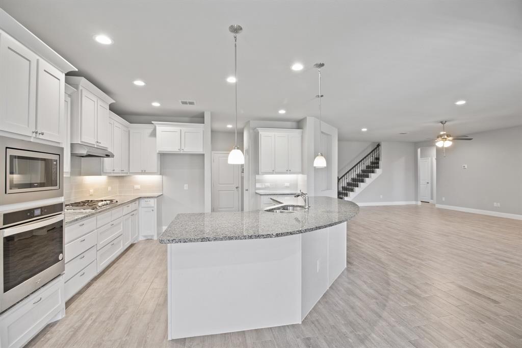 a large kitchen with stainless steel appliances kitchen island a large counter top and a wooden floors