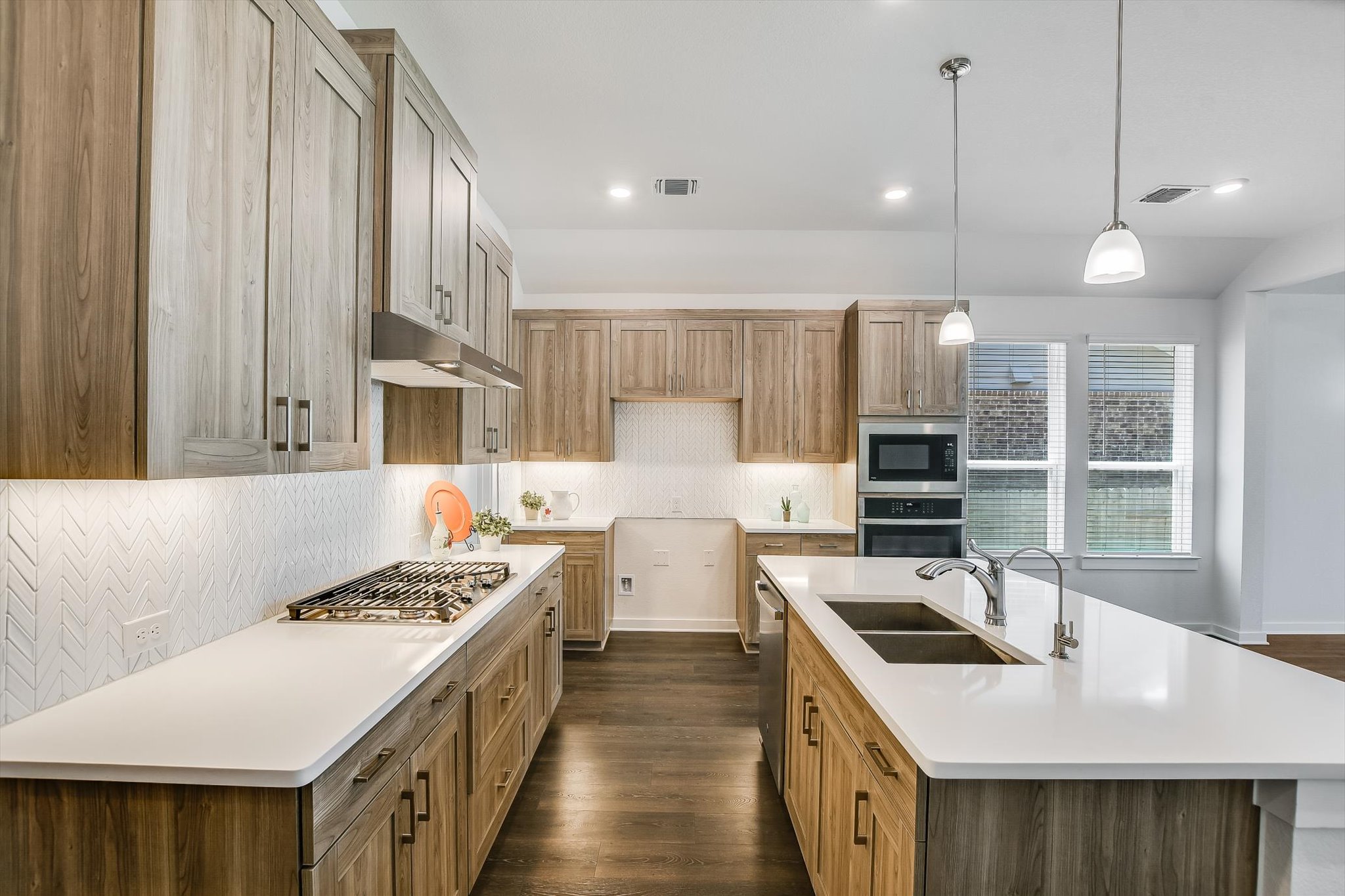 205 Wingstem Way Georgetown, TX 78633 - Photo 6 of 29 Modern kitchen featuring wood-finish cabinetry, white countertops, and a herringbone-patterned backsplash. Built -in oven and microwave with 5-buner gas cooktop.