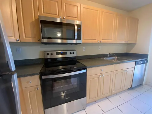 a kitchen with granite countertop white cabinets and stainless steel appliances
