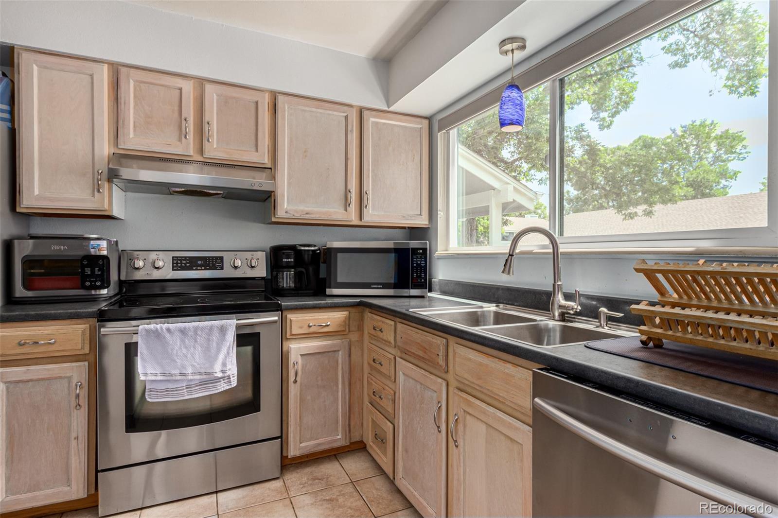 8140 West 90th Avenue Westminster, CO 80021 - Photo 11 of 47 a kitchen with stainless steel appliances granite countertop a sink a stove and a microwave