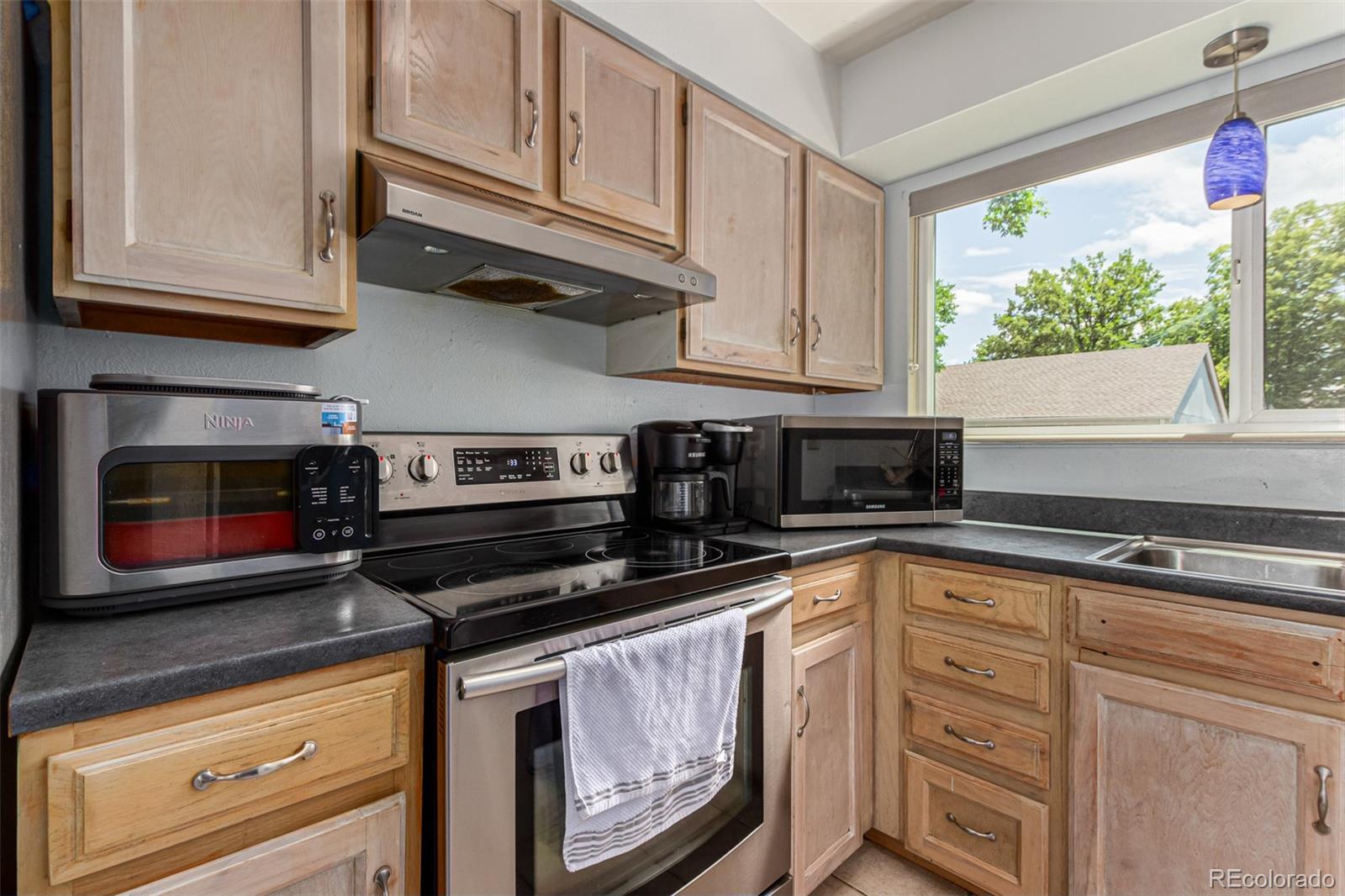 8140 West 90th Avenue Westminster, CO 80021 - Photo 13 of 47 a kitchen with granite countertop white cabinets appliances and a window