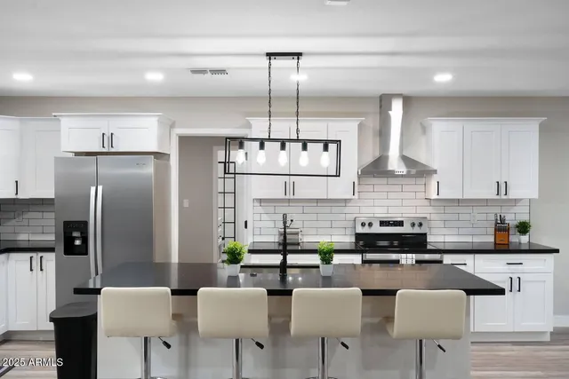 a kitchen with stainless steel appliances kitchen island granite countertop a refrigerator a stove a sink a dining table and chairs