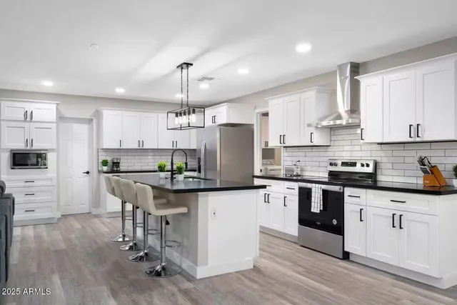 a kitchen with stainless steel appliances kitchen island granite countertop a table chairs refrigerator and sink