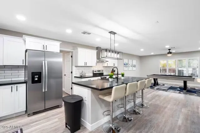 a kitchen with stainless steel appliances a stove a refrigerator a sink dishwasher and a dining table with wooden floor