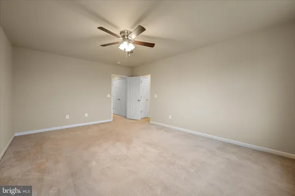 an empty room with chandelier fan and window