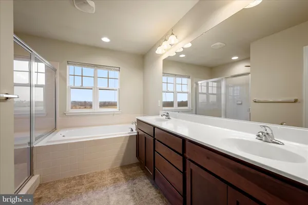 a bathroom with a tub double sink window and mirror