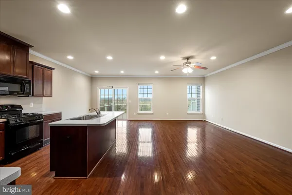 a kitchen with stainless steel appliances kitchen island granite countertop a stove a sink a refrigerator and wooden floor