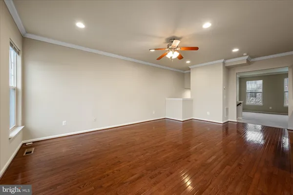 an empty room with wooden floor and chandelier fan