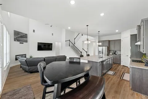 a living room with furniture kitchen view and a wooden floor